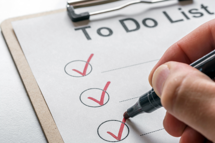 Hand mit Stift Hand mit Stift, die Haken auf einer To-Do-Liste abhakt.